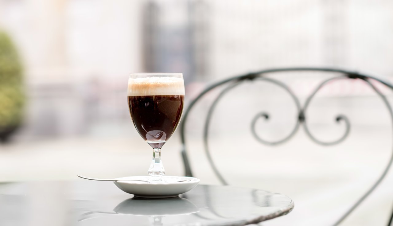 Glass of black italian coffee on a white table outside